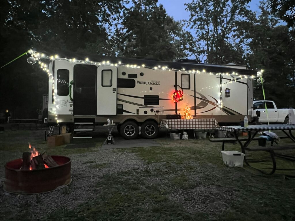 A camper trailer is lit up with christmas lights