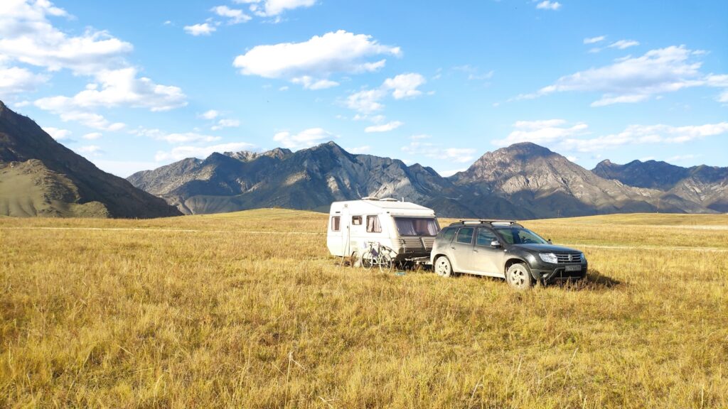 black suv on brown grass field near mountain under blue sky during daytime