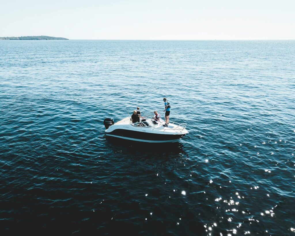 Motorboat with people cruising on the calm open sea under bright daylight.