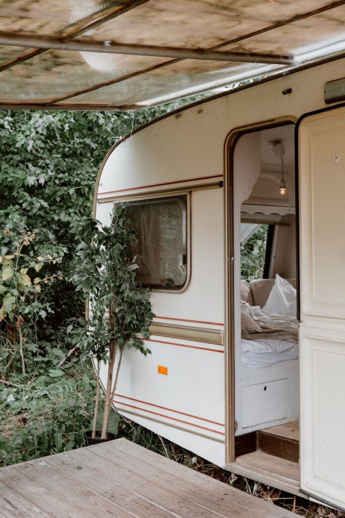 A cozy camper trailer surrounded by lush greenery, offering an inviting retreat in nature.