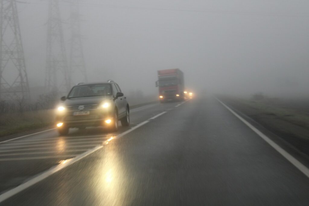 a couple of cars driving down a foggy road