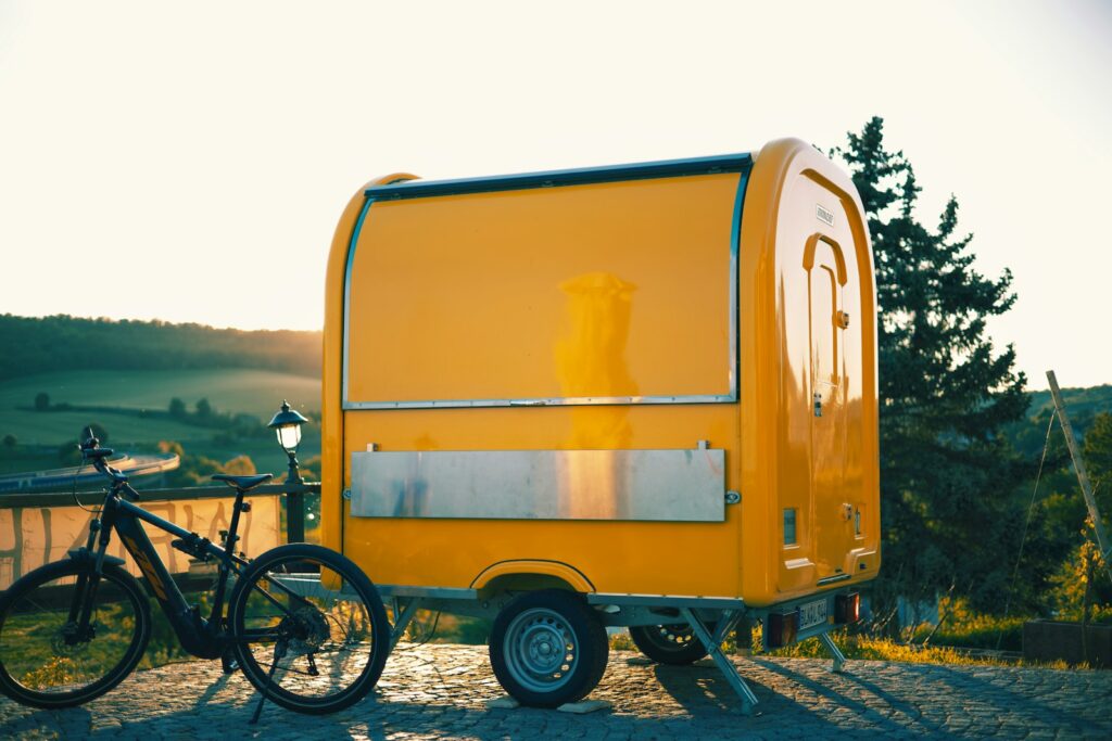A yellow trailer and bicycle outside in the sunlight.