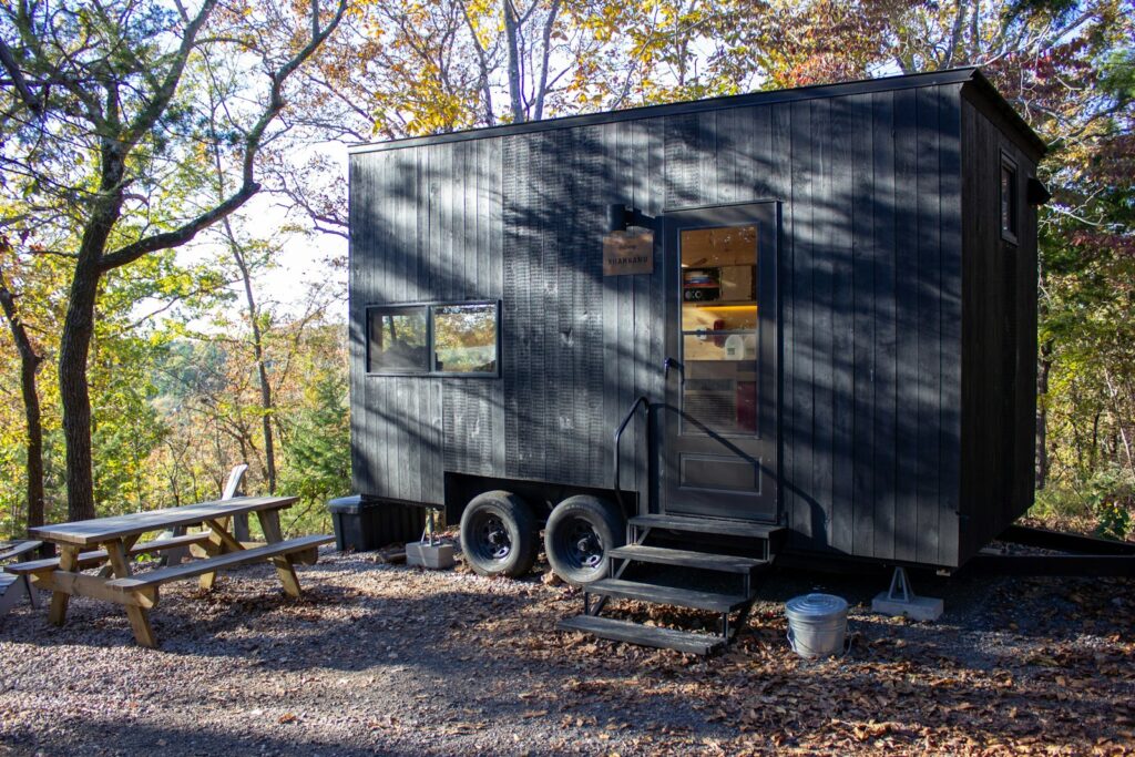 A dark tiny house with a picnic table outside.