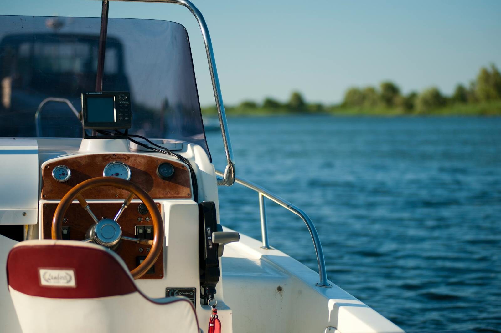 A yacht steering wheel with a serene water view during a bright summer day offering leisure and adventure.
