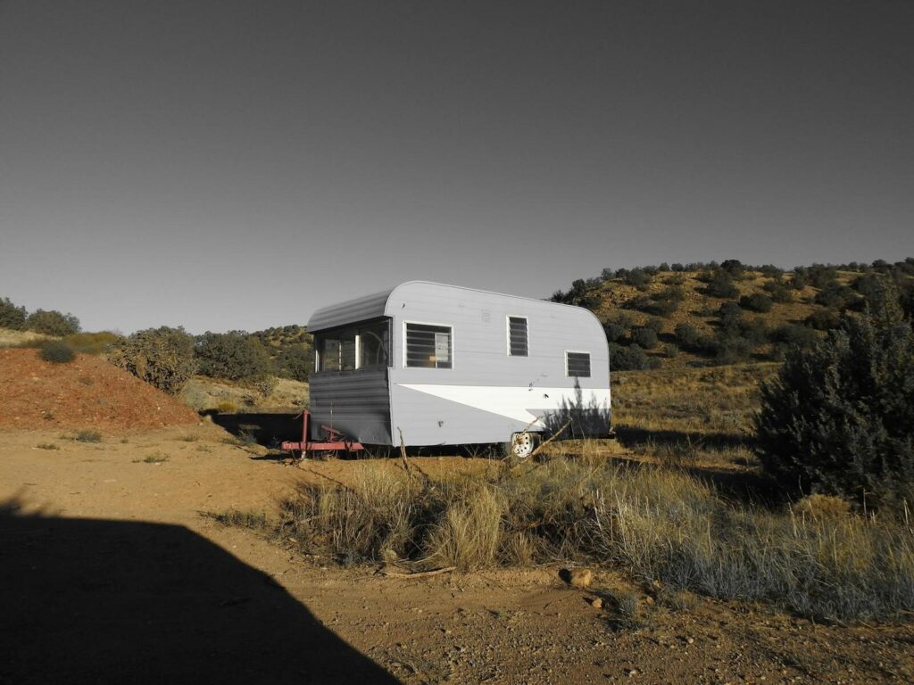 A vintage caravan parked in a serene desert setting under clear skies, perfect for travel enthusiasts.