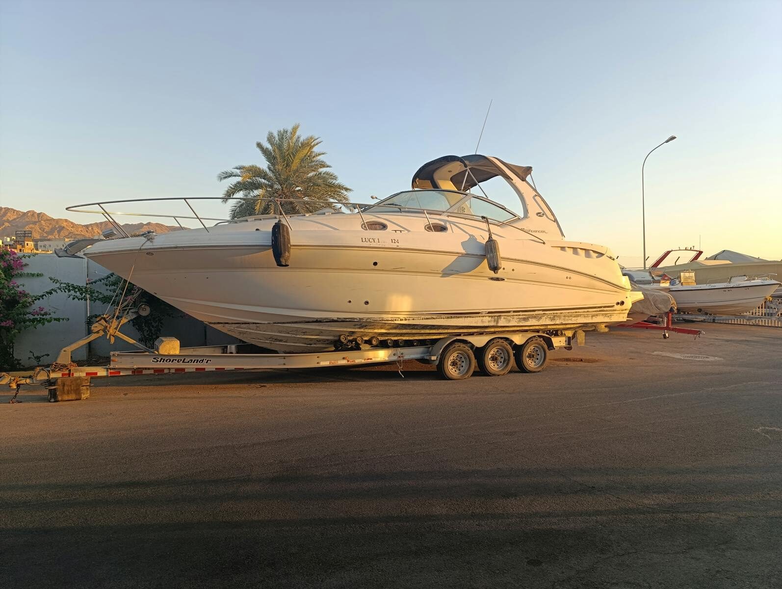 Elegant yacht on trailer at Aqaba Marina during golden hour, showcasing a serene luxury lifestyle.