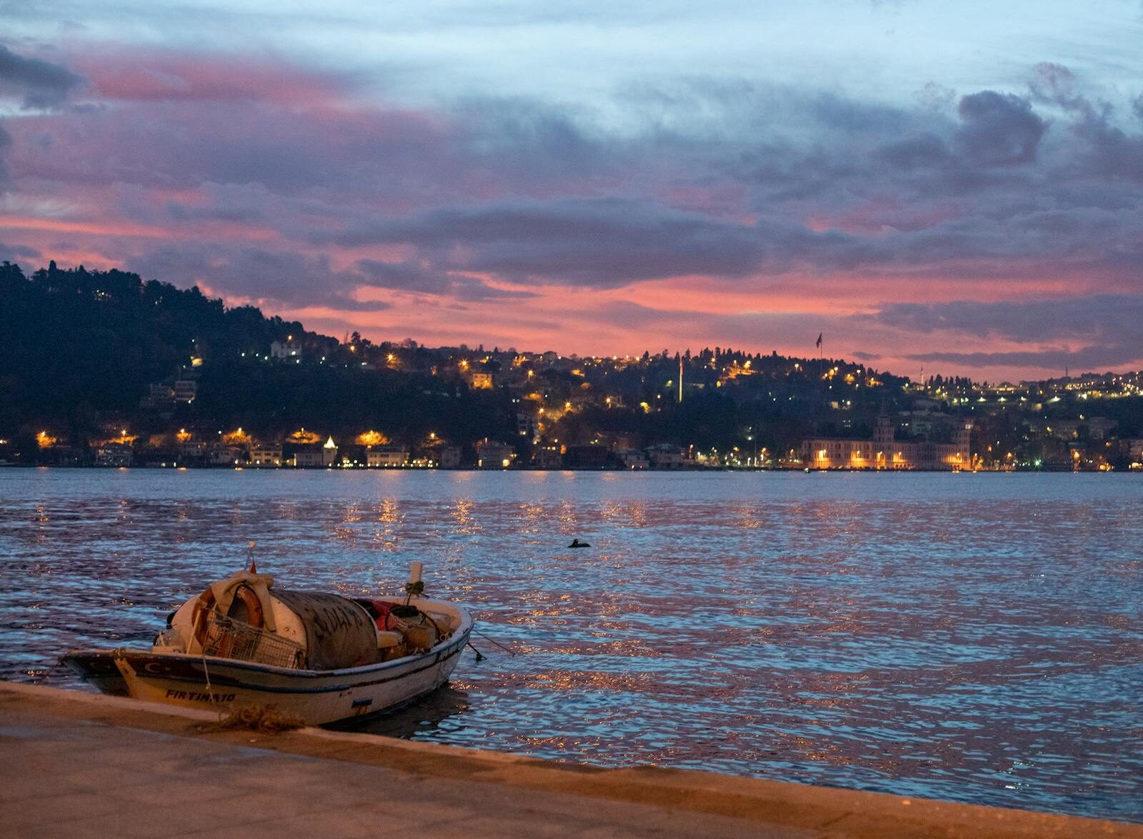 Idyllic view of a small boat on the Bosphorus at sunset with Istanbul's skyline in the background.