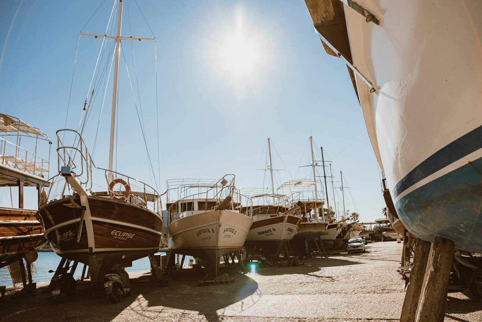 A row of boats in dry dock under a bright sun, ready for maintenance work.