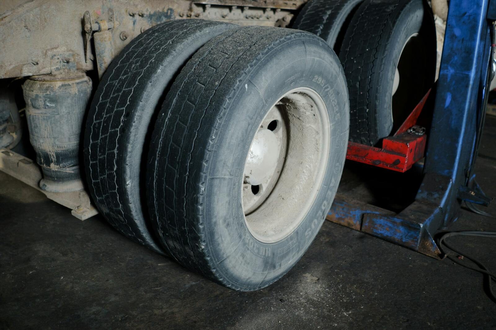 Photo by cottonbro studio Close-up of truck tires in a garage awaiting maintenance. Industrial setting with a focus on wheels.