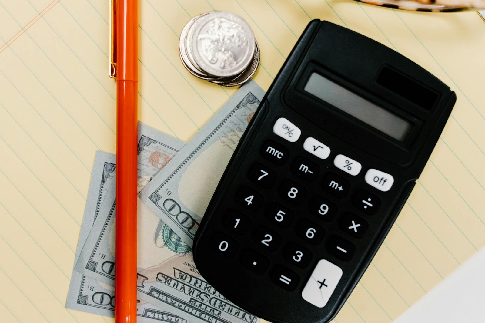Photo by Tara Winstead Close-up image of a calculator, pen, and currency on a yellow notepad, symbolizing finance.