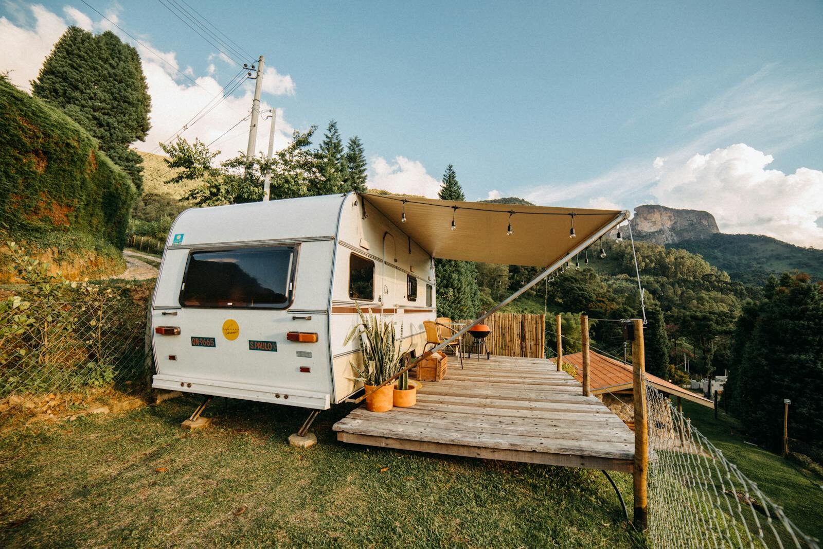 Tranquil outdoor campsite with caravan, deck, and picturesque mountain landscape.