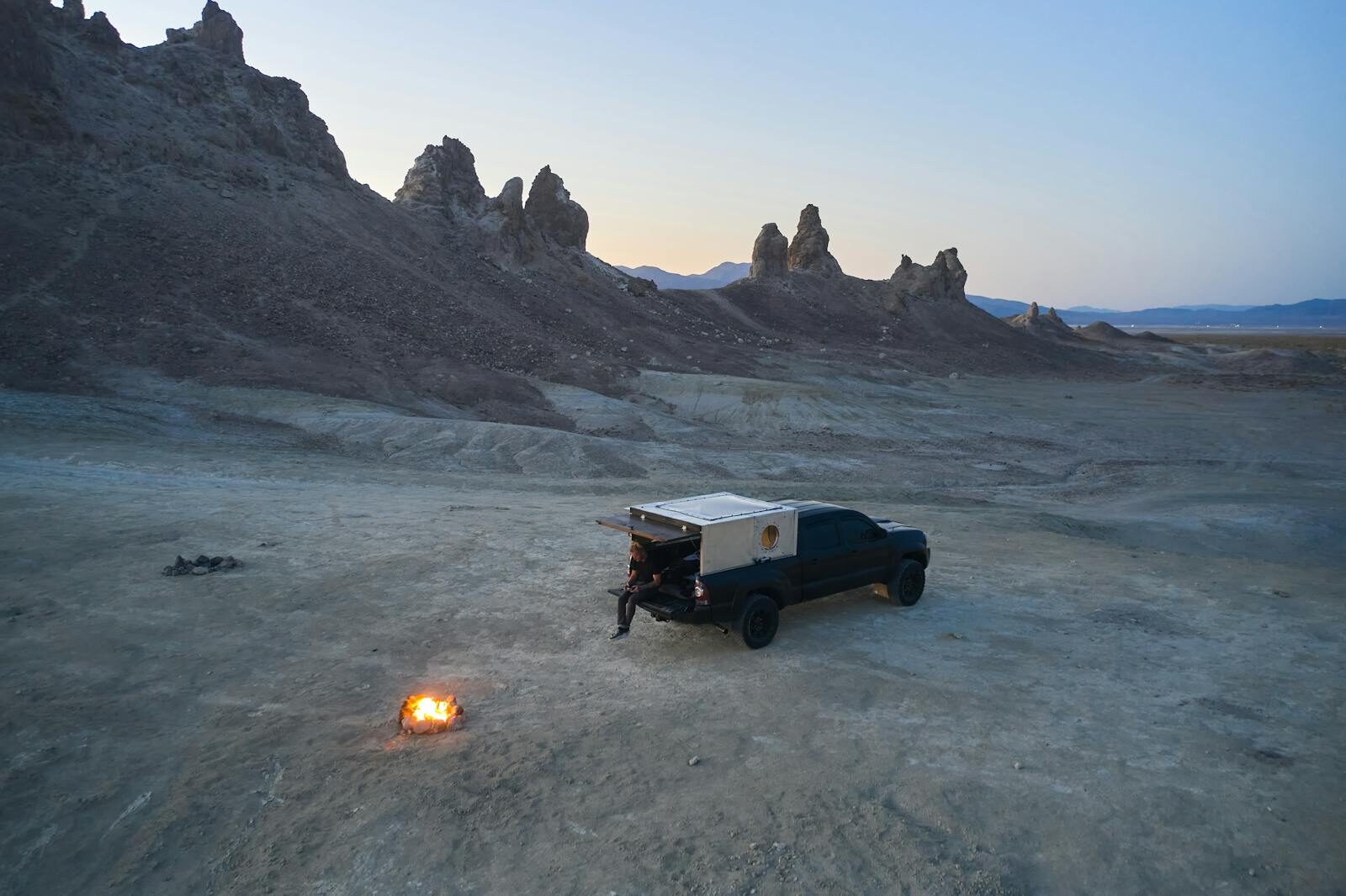 Tranquil desert camping at dusk with a pickup truck and campfire in Trona Pinnacles.