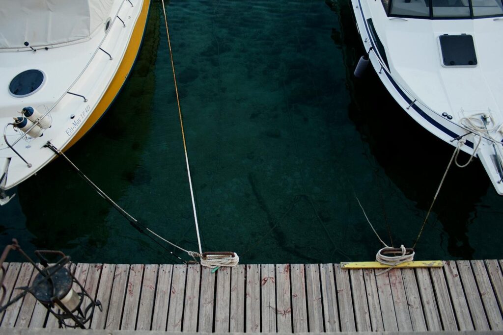 Aerial view of boats docked on crystal-clear waters at a wooden dock in Rodos, Greece.