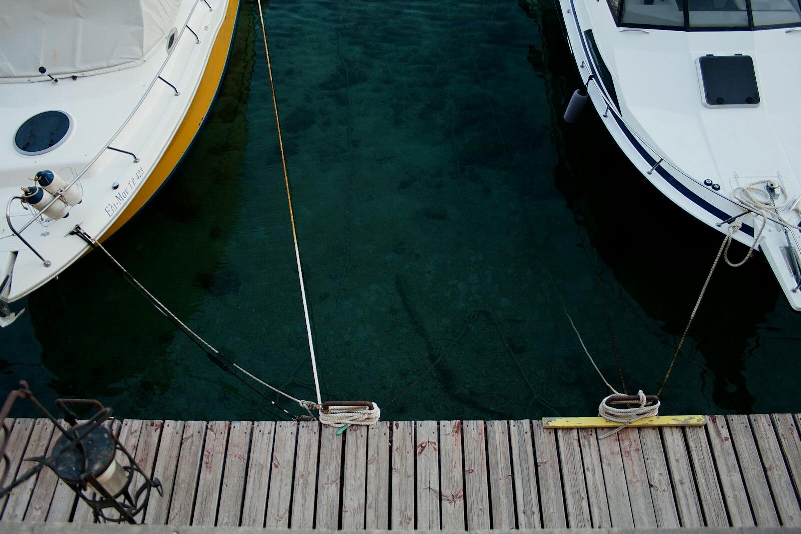 Aerial view of boats docked on crystal-clear waters at a wooden dock in Rodos, Greece.