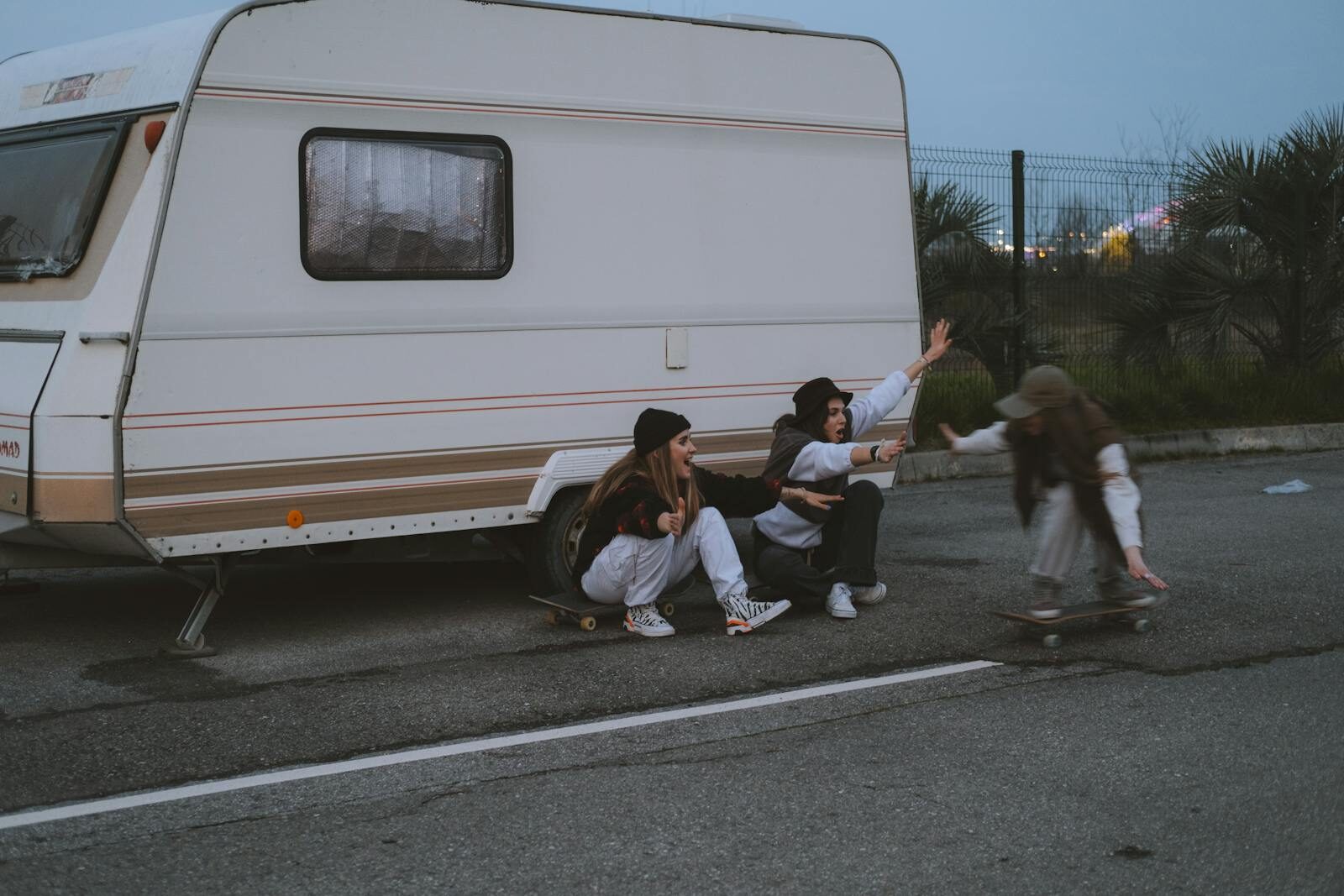 Teenagers enjoying skateboarding near a camper during evening hours. Street culture and fun vibes.