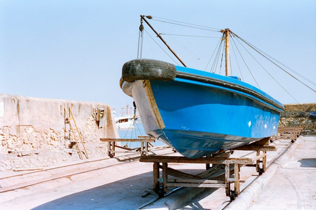 A bright blue boat rests on a wooden trailer.