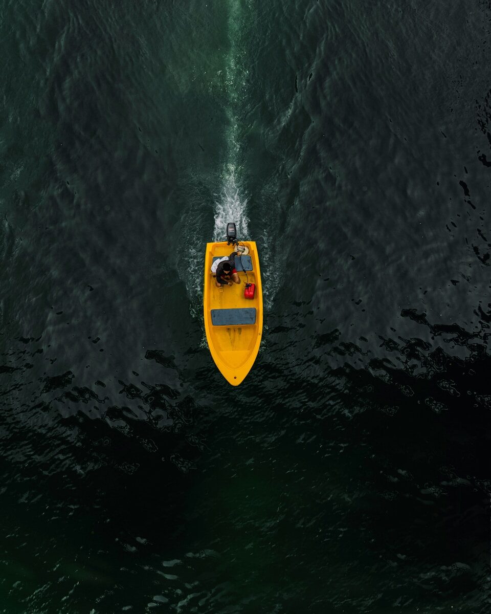 a small yellow boat in the middle of a large body of water