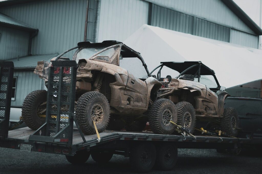 Two damaged off-road vehicles on a flatbed trailer.