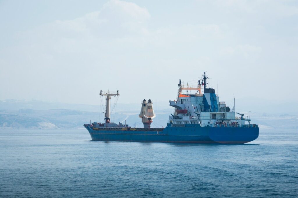 A blue cargo ship sails on a calm sea.