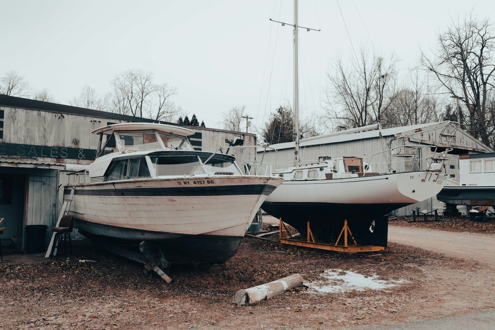 Two boats sit on dry land in front of a building.