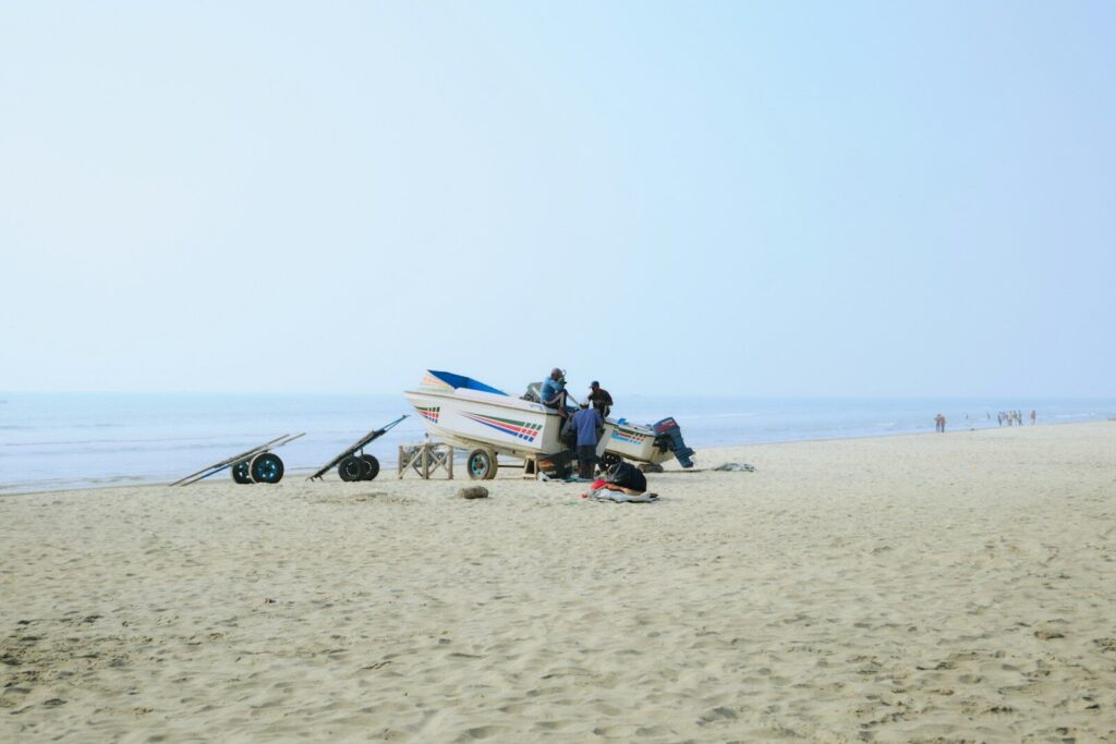 People gathered around a boat on a sandy beach.