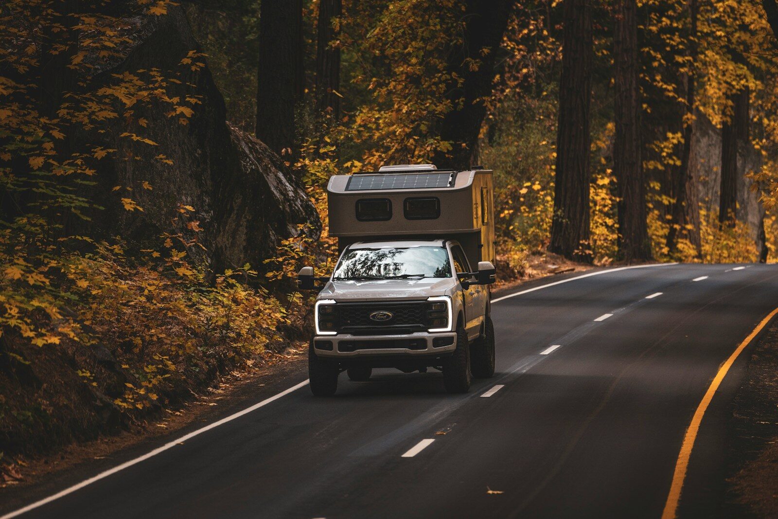 A truck driving down a road in the woods