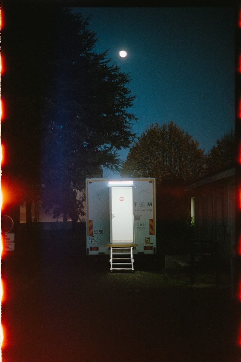 A portable toilet illuminated at night under the moon.