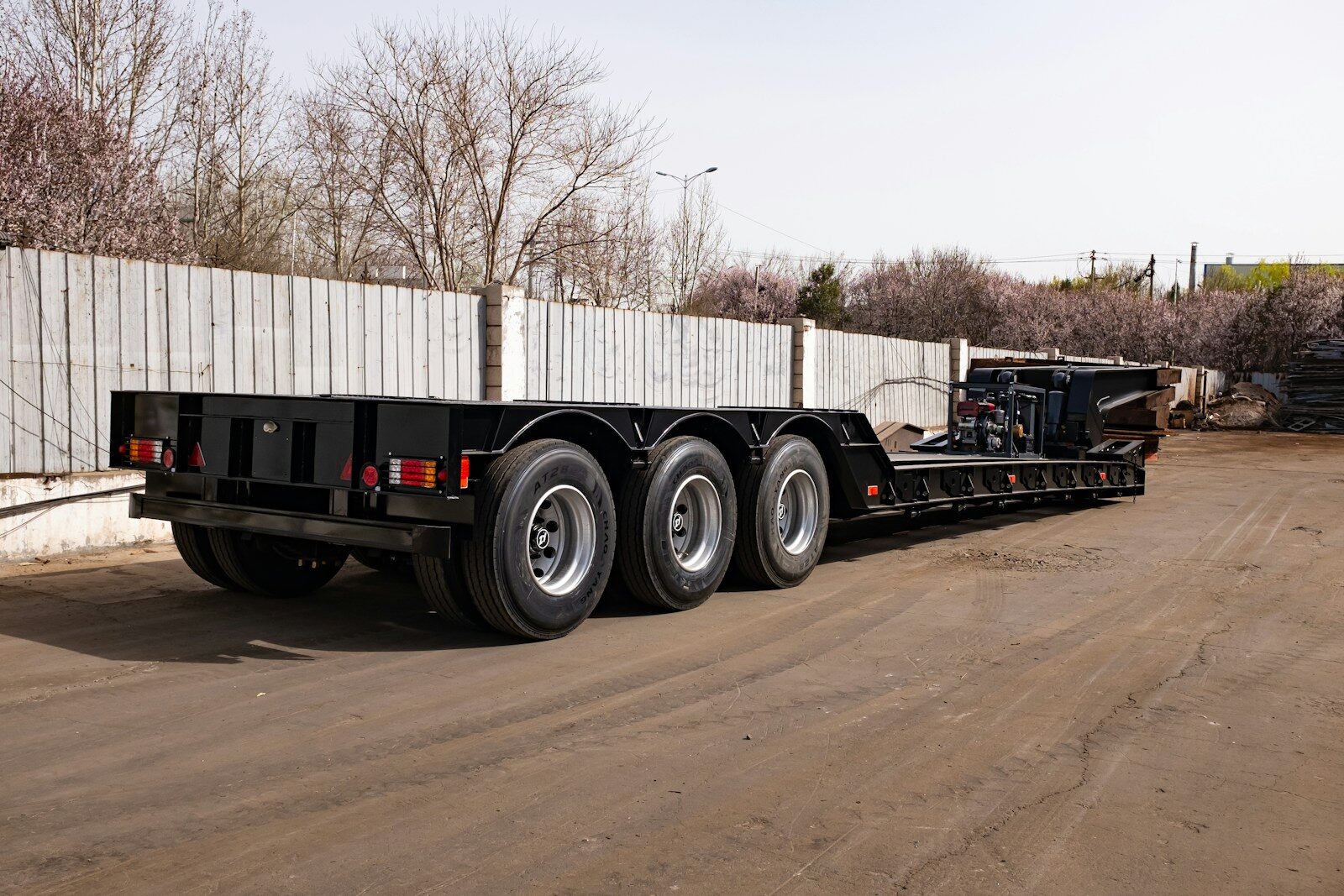 Photo by Forest Plum A black triple axle trailer parked on pavement.