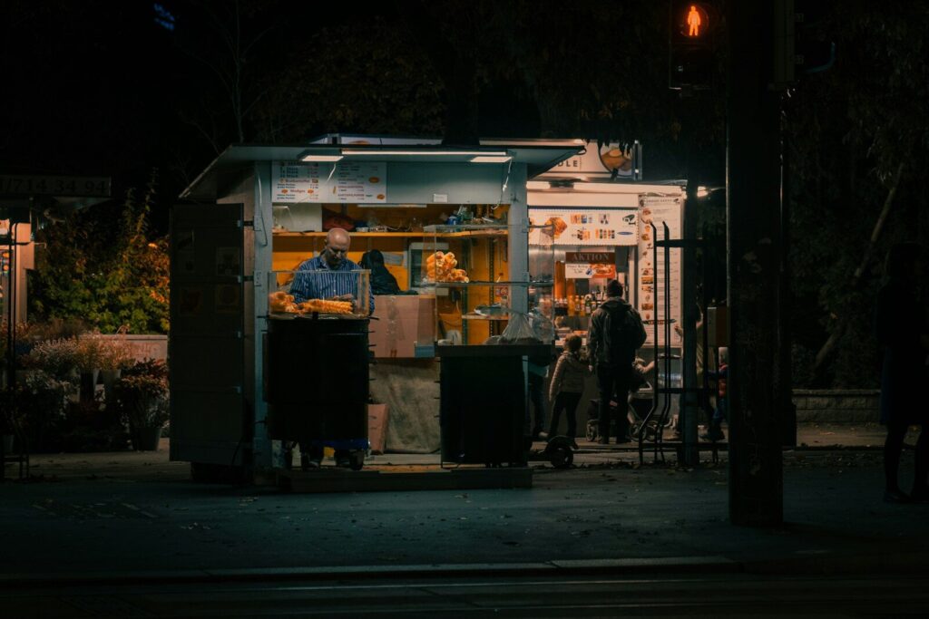 a couple of people standing outside of a store at night