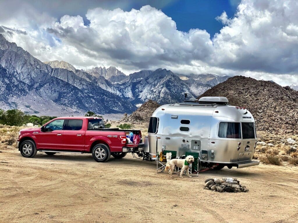 a red truck pulling a trailer with a camper on it