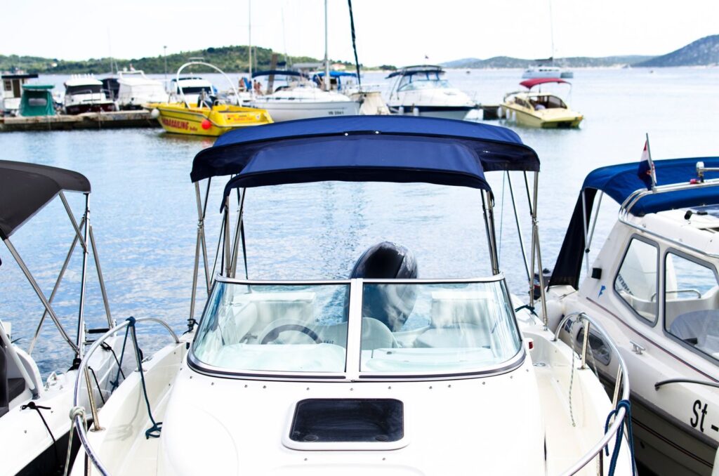 A serene marina scene featuring multiple boats docked on calm waters under a blue sky.
