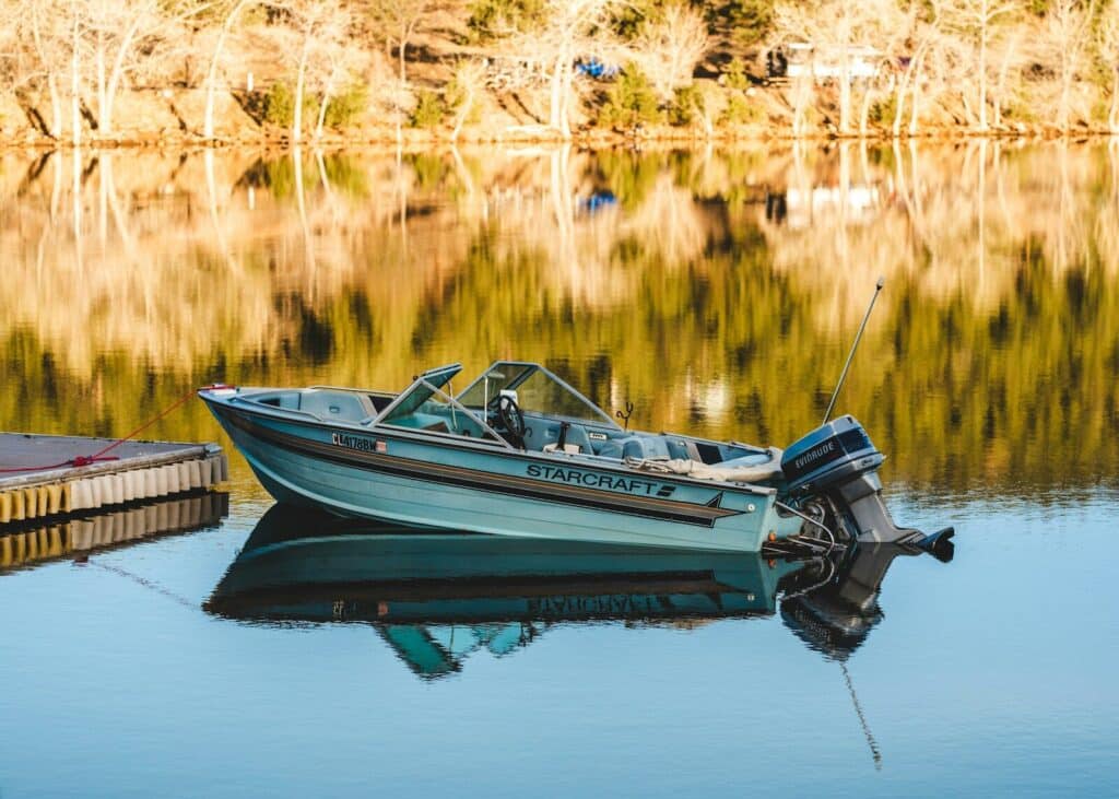 a small boat sitting on top of a lake next to a dock