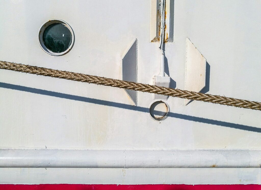 Close-up of a ship's white hull with a porthole.