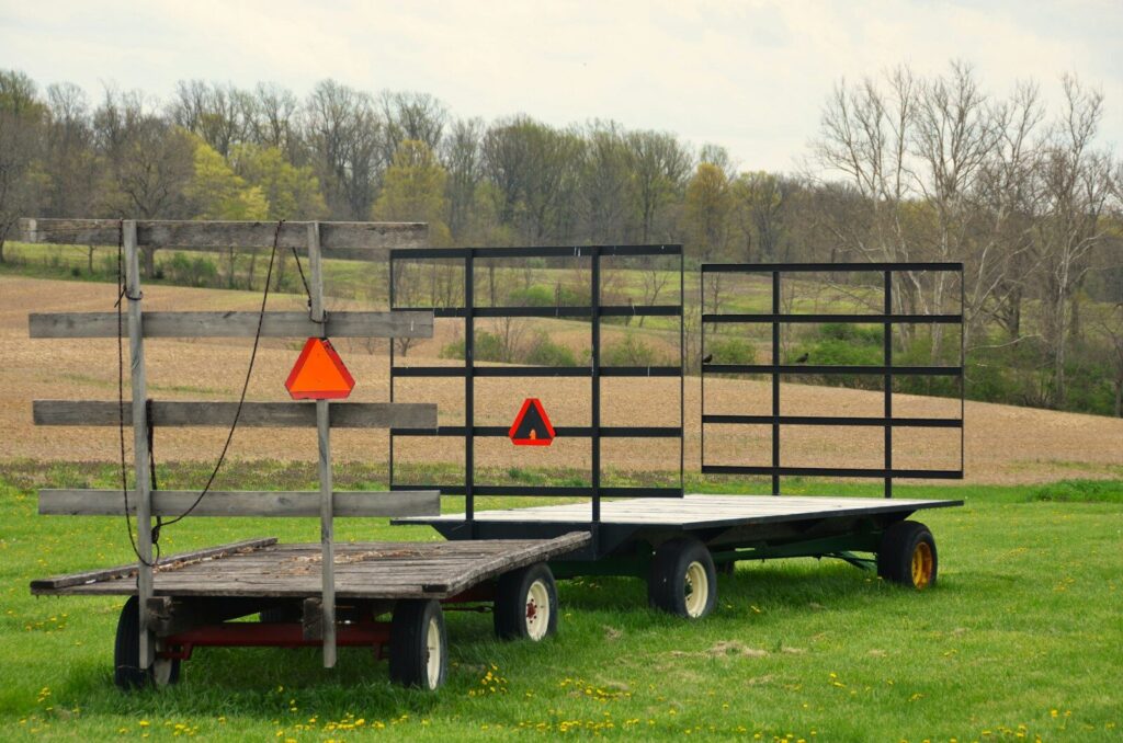 Two farm wagons are parked in a green field.