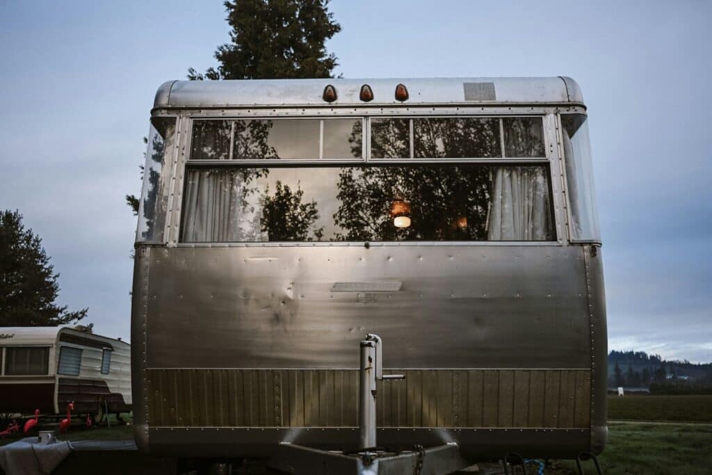 A vintage silver travel trailer parked outdoors at dusk.