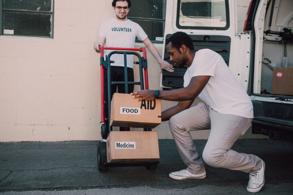 Volunteers organizing and loading boxes of aid, food, and medicine for donation.