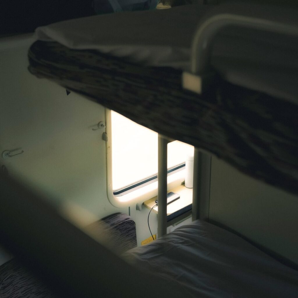Interior shot of a bunk bed in a train compartment with natural light from the window.